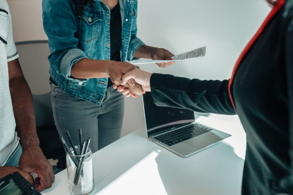 pexels photo 7979601 7979601 Two people shaking hands over a desk signifies a business agreement or partnership.